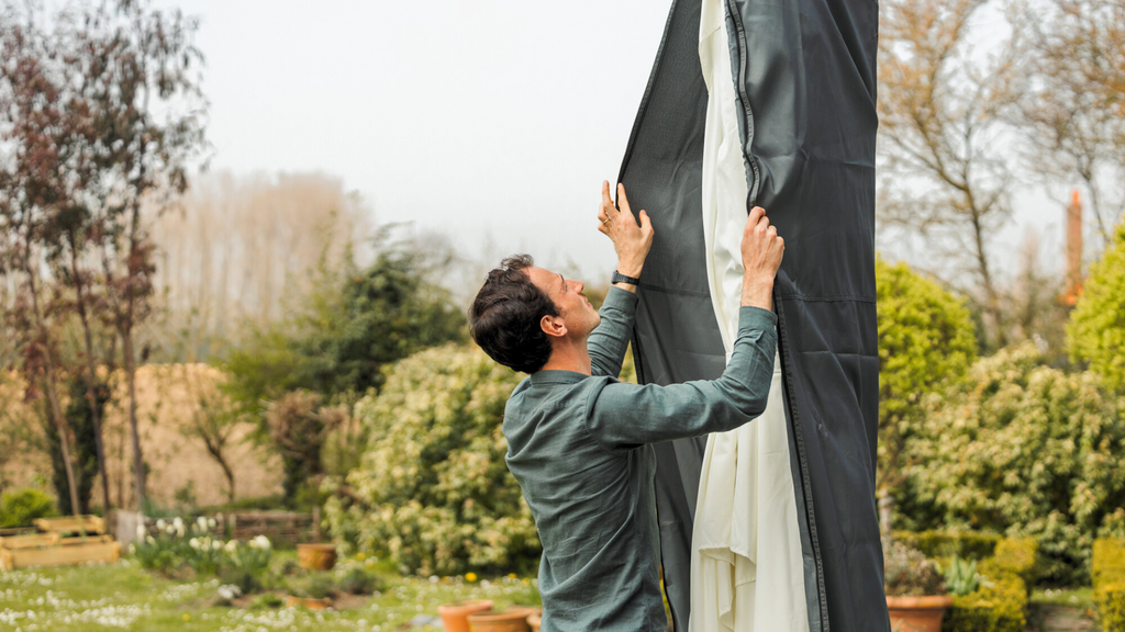 Un homme qui remet la housse de protection de son parasol