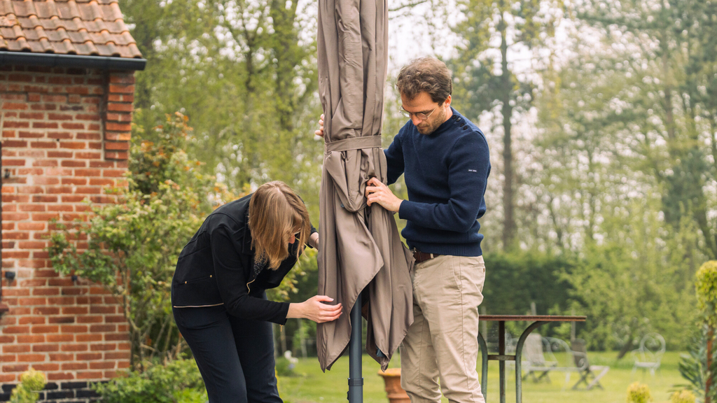 Deux personnes installant leur parasol dans leur jardin 