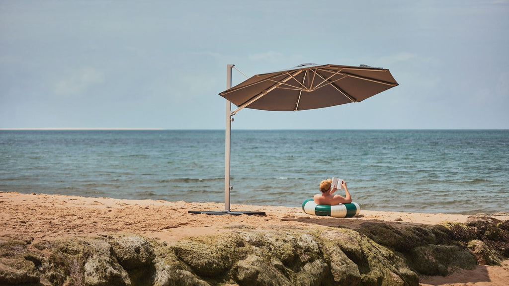 Un homme à la plage lisant un livre sous son parasol