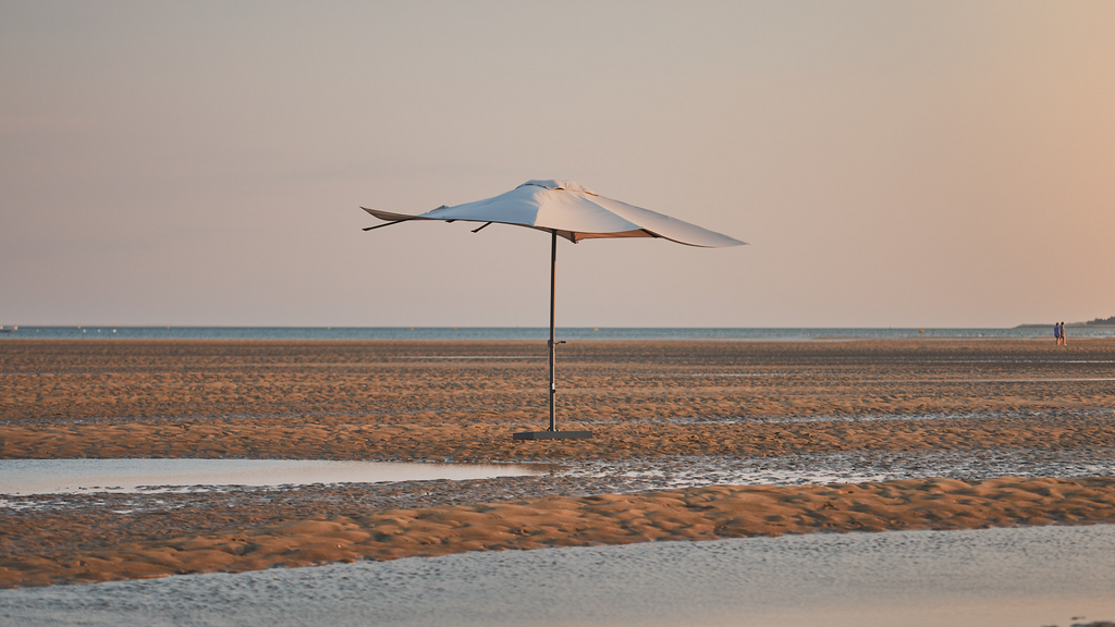 Un parasol droit avec une toile écru sur le sable